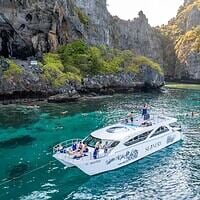 Crystal-clear turquoise boat cruise exploring limestone cliffs and lush green scenery in Thailand.