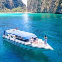 Secluded boat cruising in Thailand's turquoise waters with scenic cliffs in the background.
